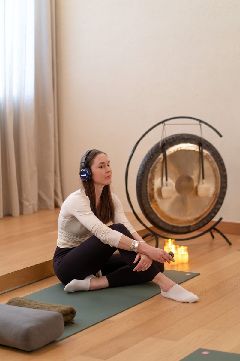 A facilitator in headphones sitting by a gong
